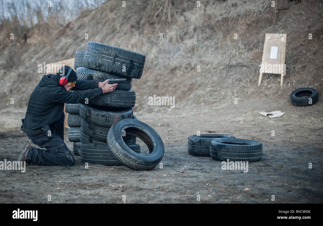 Pistola di combattimento addestramento al tiro da dietro e intorno al coperchio o barricade. Advanced combattimenti tattici corsi di tiro sul poligono di tiro Foto Stock