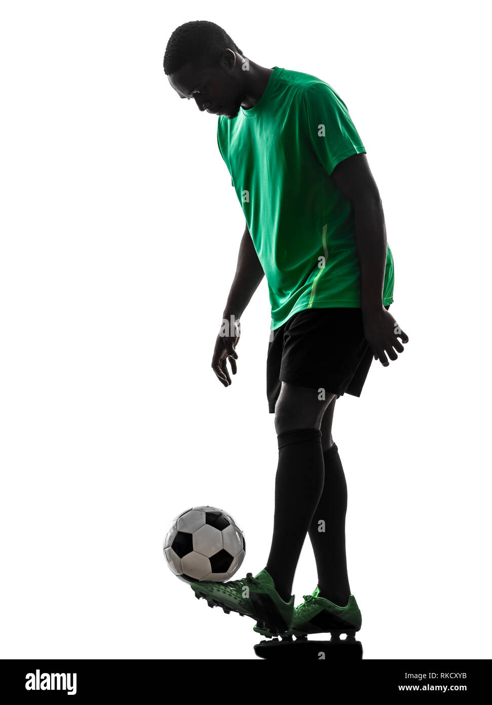 Un uomo africano giocatore di calcio maglia verde La giocoleria in silhouette su sfondo bianco Foto Stock
