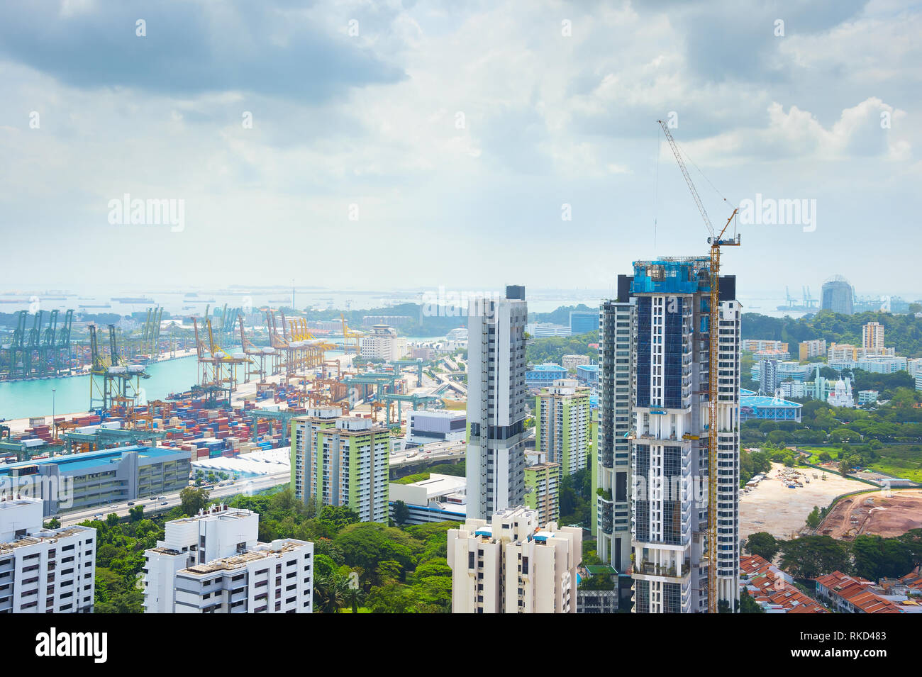 Sito in costruzione del grattacielo moderno in corso. Industriali porta cargo in background. Singapore Foto Stock