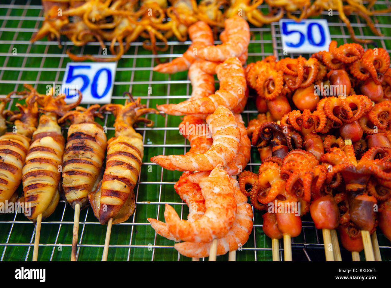 Una disposizione di spiedini di pesce alla griglia consistente di calamari,  polpi, calamari e gamberi sbucciato Thai street food snack e stuzzichini in  un pesce m Foto stock - Alamy