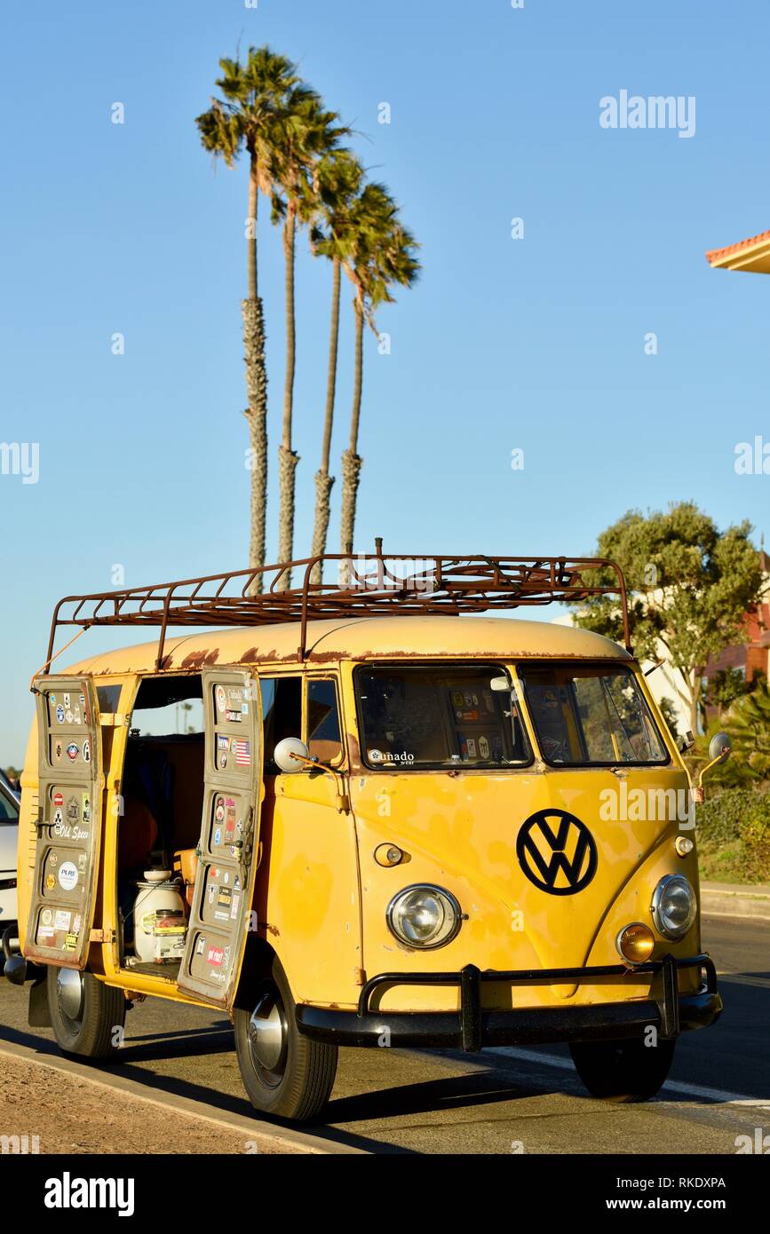 Classico degli anni sessanta giallo Volkswagon VW minibus camper parcheggiato a Sunset Cliffs al tramonto, porte aperte con palme, San Diego, Stati Uniti d'America Foto Stock