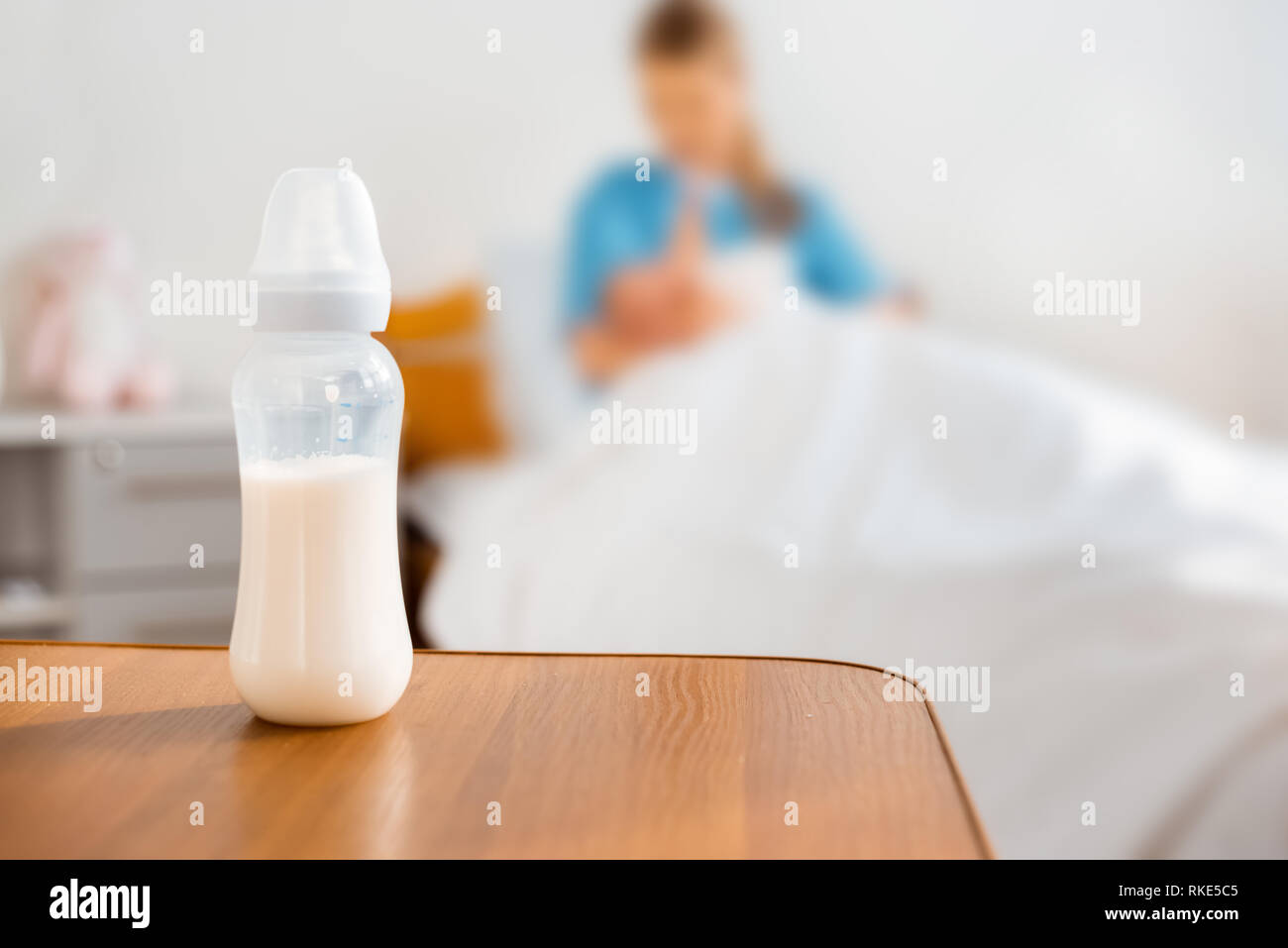 Vista ravvicinata di biberon con latte e madre allattamento neonato nella stanza di ospedale Foto Stock