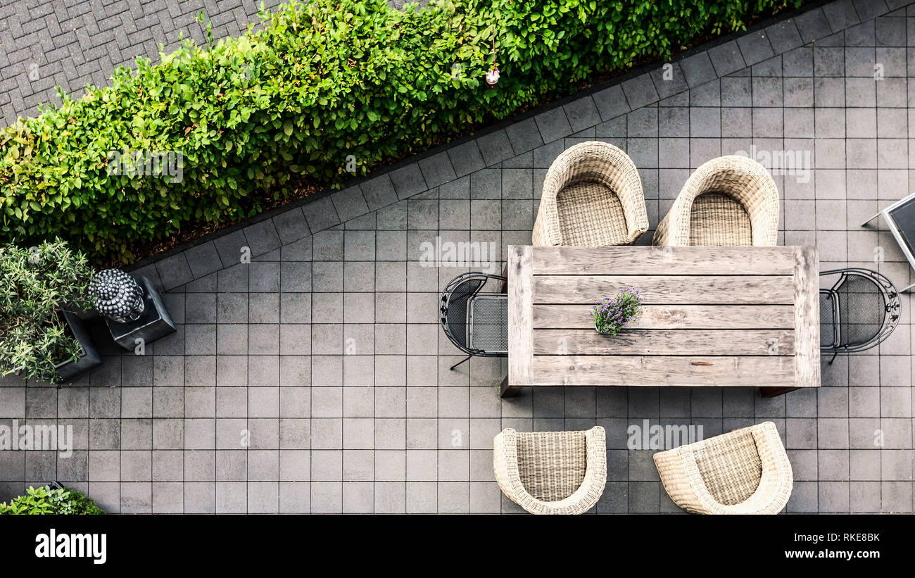 Moderno patio terrazza con tavolo e sedie di rattan circondato da vegetazione lussureggiante, ad alto angolo di visione. Area relax Foto Stock