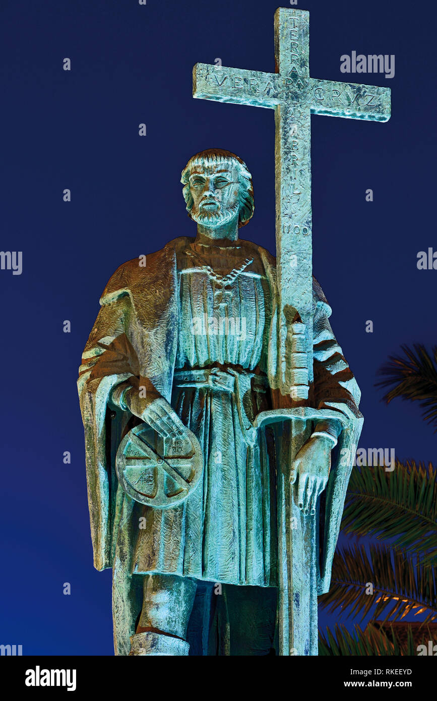 Orologio notturno illumina la statua del navigatore medievale con croce Foto Stock