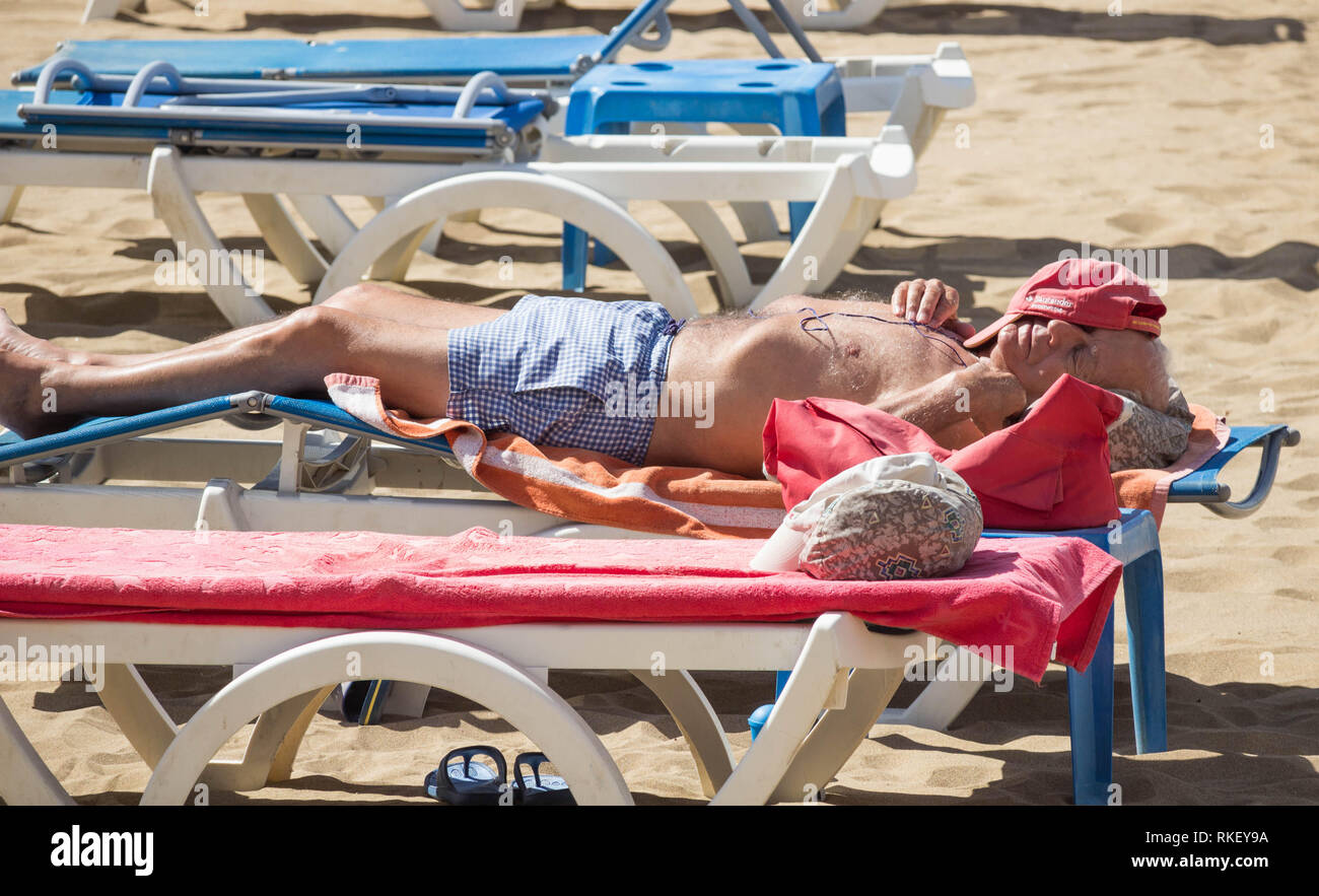 Uomo maturo a prendere il sole sulla spiaggia in Spagna Foto Stock