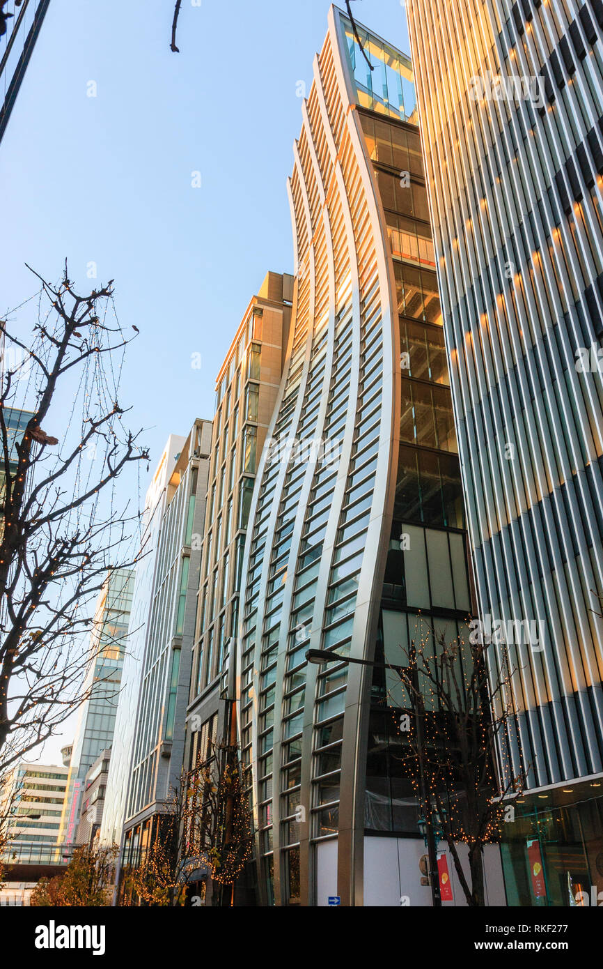 Tokyo, Ginza, ora d'oro. Ondulate in acciaio inox la facciata della V88 edificio, ex De Beers Ginza, con le luci di Natale alberi all'esterno. Foto Stock