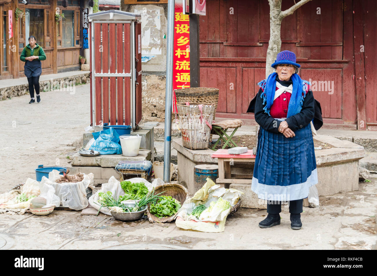 Naxi donna vendita di ortaggi per le strade del villaggio di Baisha, Yunnan, Cina Foto Stock