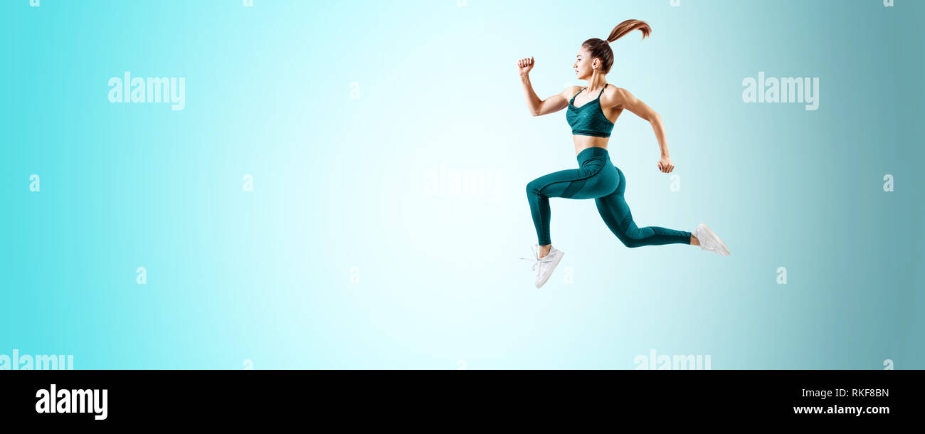 Giovane donna runner in blu sportswear saltare in aria. Movimento dinamico. Foto Stock
