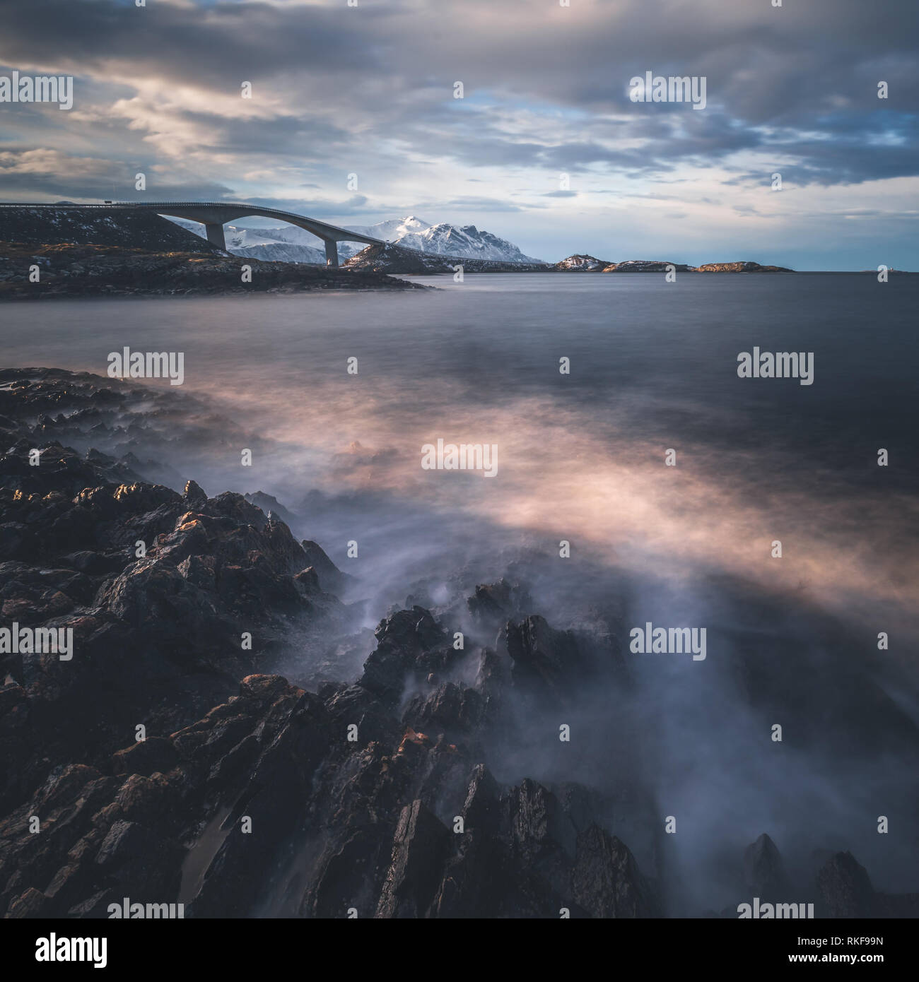 Costa rocciosa dall'Oceano Atlantico strada in Norvegia. Scatti con lunghi tempi di esposizione. Vista sul famoso ponte Storseisundbrua e le onde che si infrangono. Foto Stock