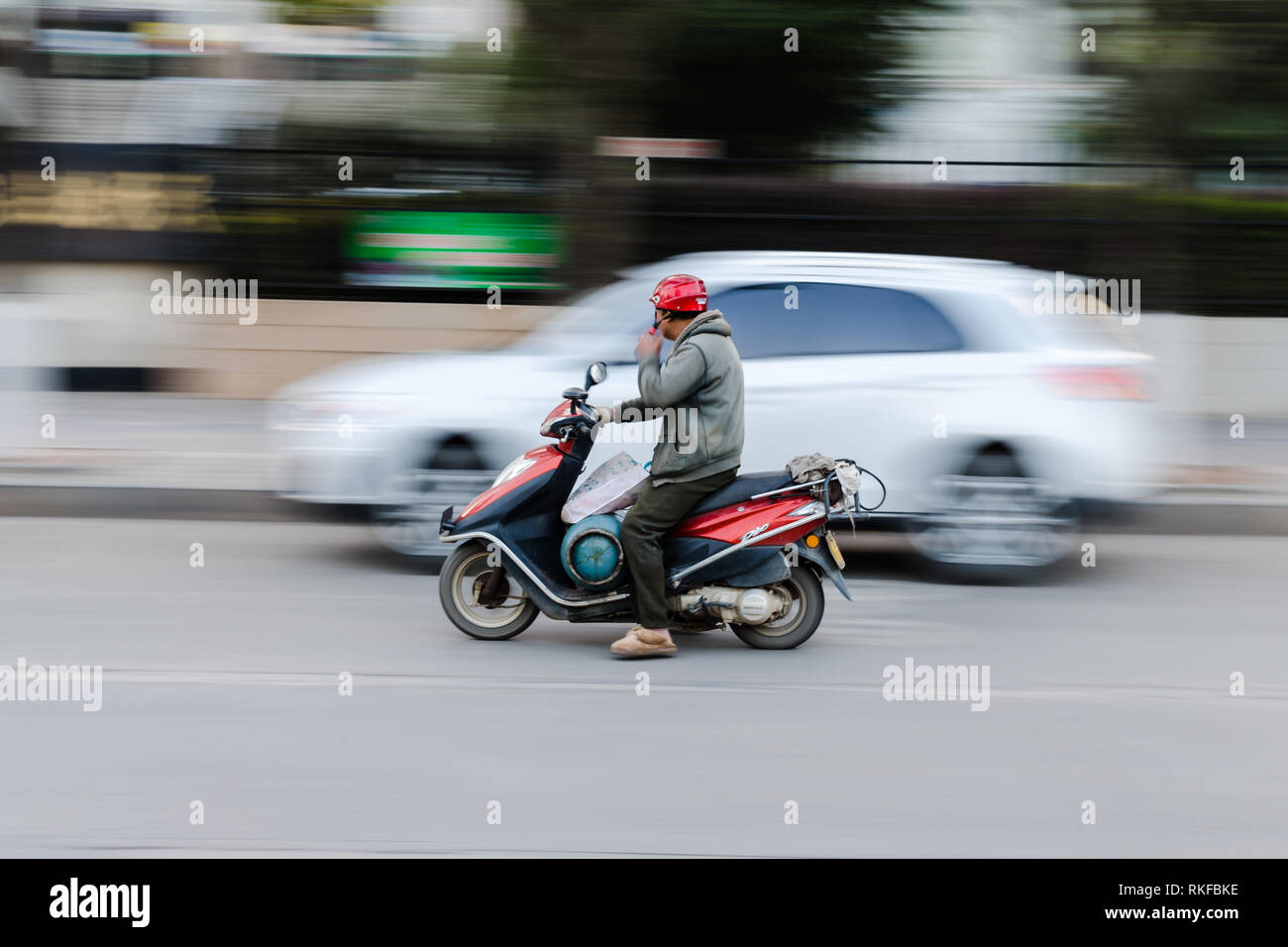 Panoramica di un uomo che porta una bottiglia di gas sulla sua moto, Dali, Cina Foto Stock