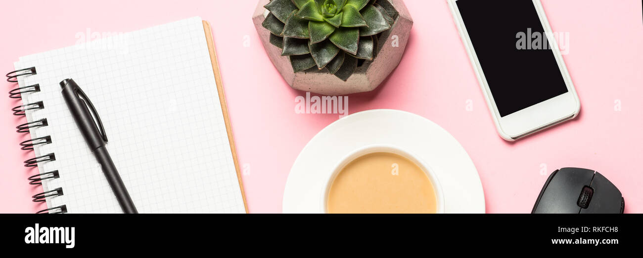 Posto di lavoro freelance con notepad, tazza di caffè, succulenti e mouse su rosa Foto Stock