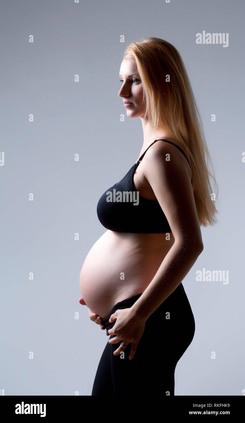 Ritratto in studio di la gravidanza di una donna bionda cercando. Foto Stock
