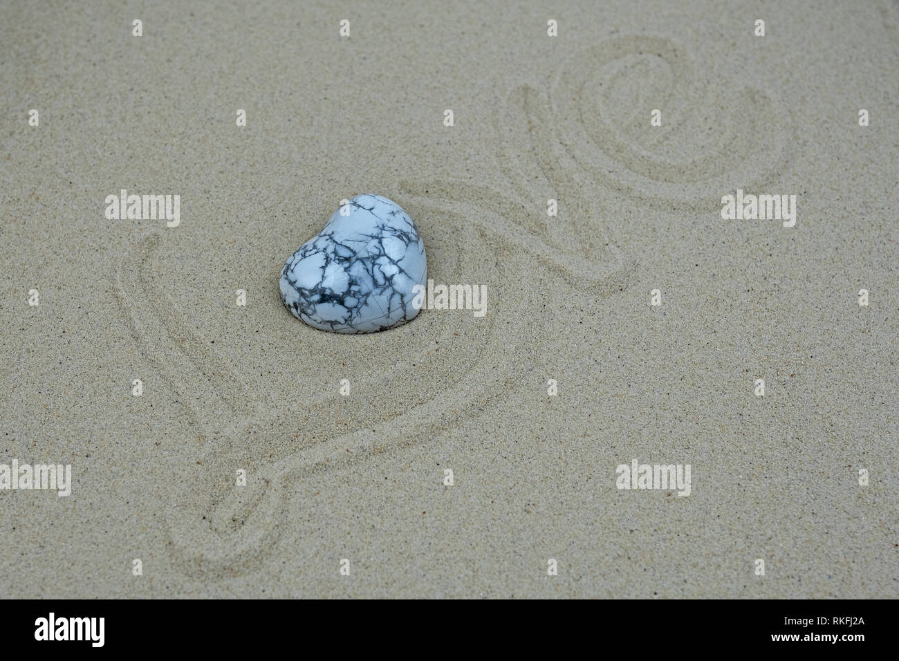 La parola amore scritte sulla sabbia, o sostituito da un cuore di marmo Foto Stock