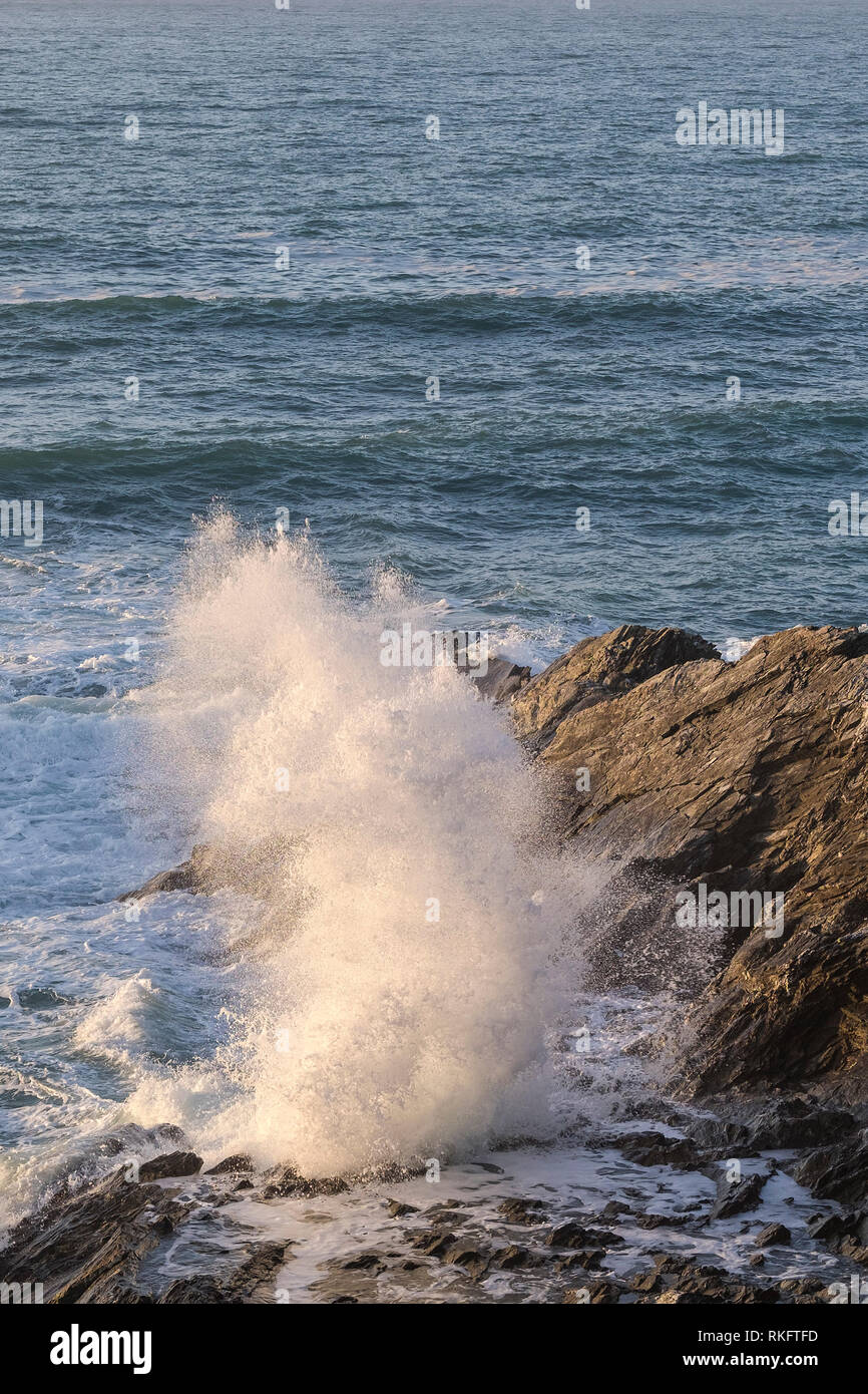 Un'onda di marea che si schiantano contro le rocce della costa di Newquay in North Cornwall. Foto Stock