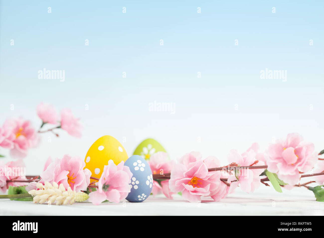 Uova di Pasqua e fiori di colore rosa decorazione su sfondo blu Foto Stock