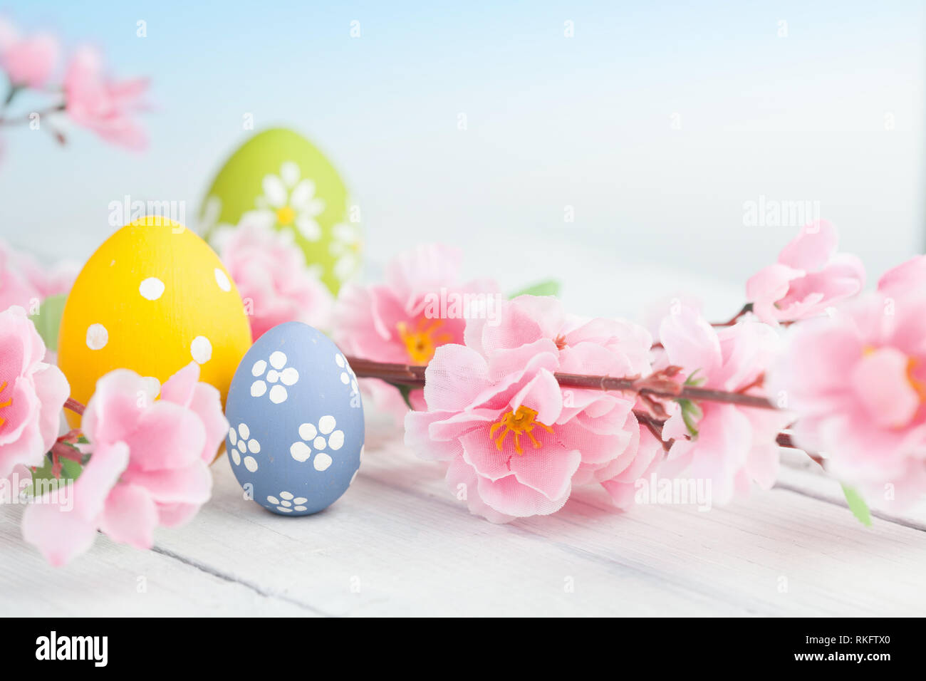 Uova di Pasqua e fiori di colore rosa decorazione su sfondo blu Foto Stock