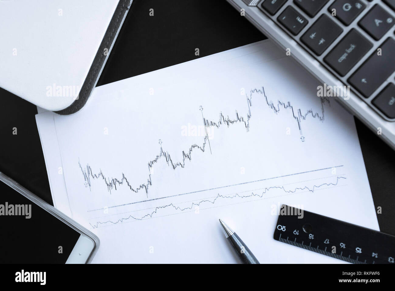 Grafico finanziario su carta bianca con i notebook computer portatile e altri articoli per ufficio sul tavolo di lavoro Foto Stock