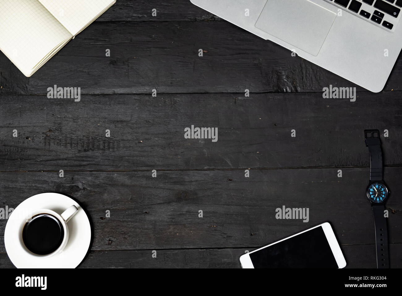 Luogo di lavoro laici piatta su sfondo nero. Laptop, appunti, caffè e telefono cellulare sulla mancanza di texture di legno, vista dall'alto Foto Stock