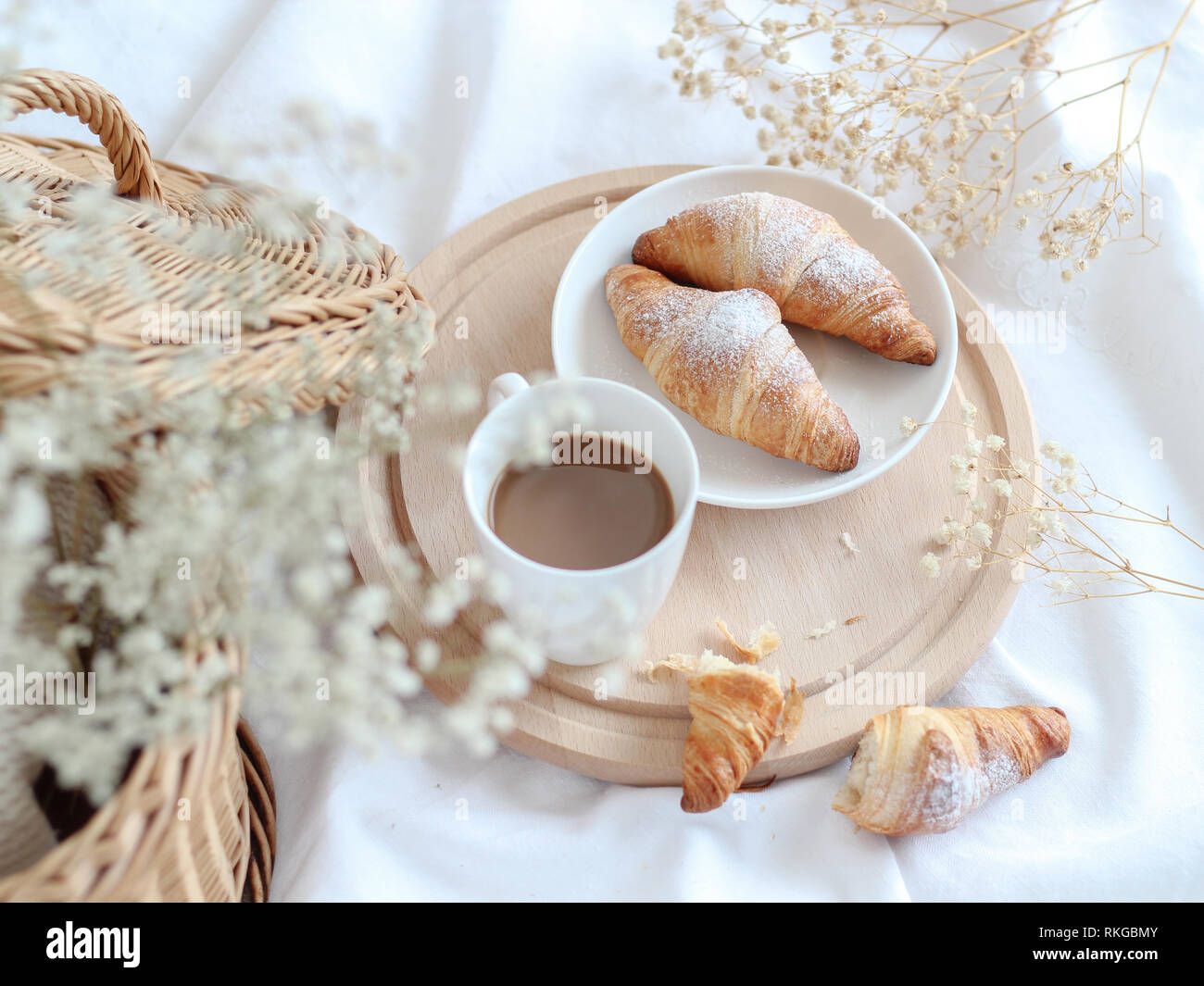 Tazza di caffè con croissant su un vassoio in legno con fiori secchi Foto Stock