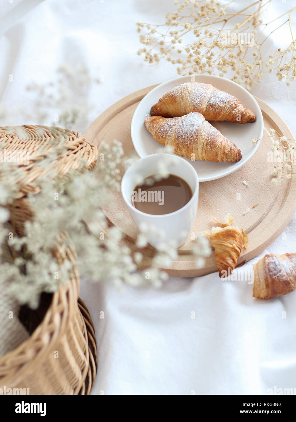 Tavolo per la colazione con una tazza di caffè e croissant, leggero e luminoso umore Foto Stock