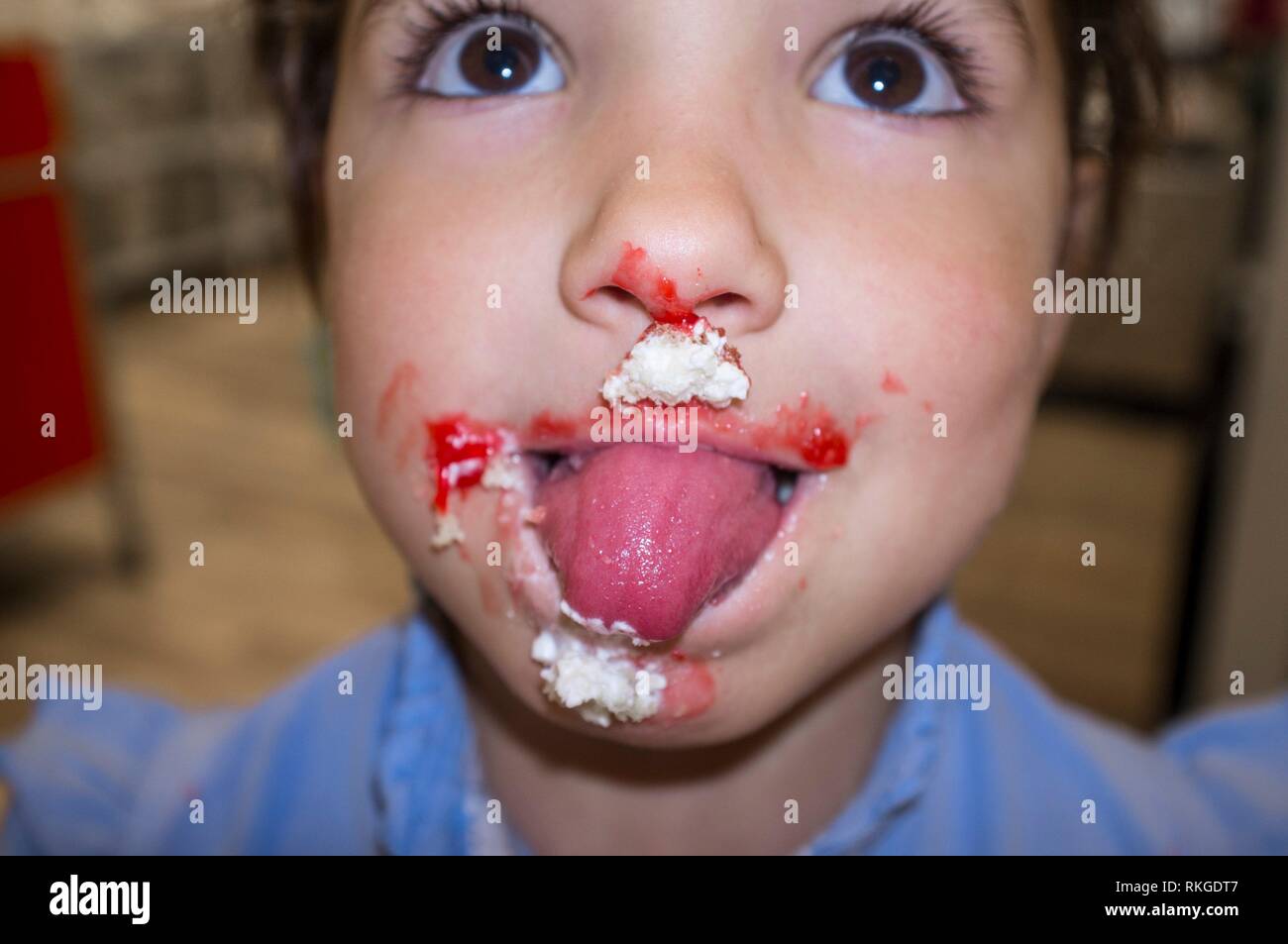 Dolce bambino dentata ragazza leccare le sue labbra. Lei ha la bocca piena di panna montata. Foto Stock
