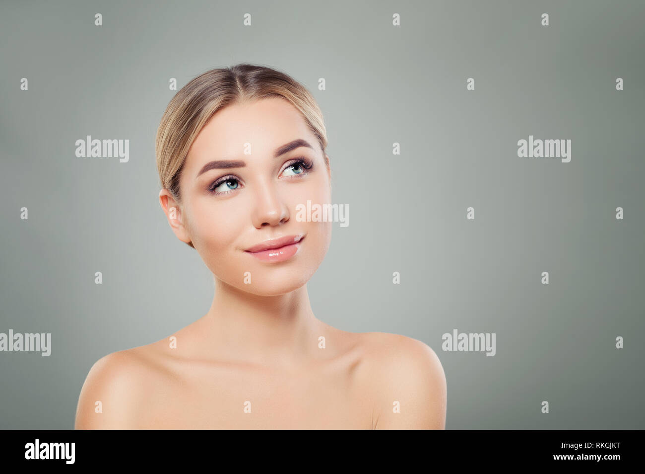 Donna sorridente con una pelle perfetta guardando in alto sullo sfondo con copia spazio. Trattamento per il viso e il concetto di cosmetologia Foto Stock