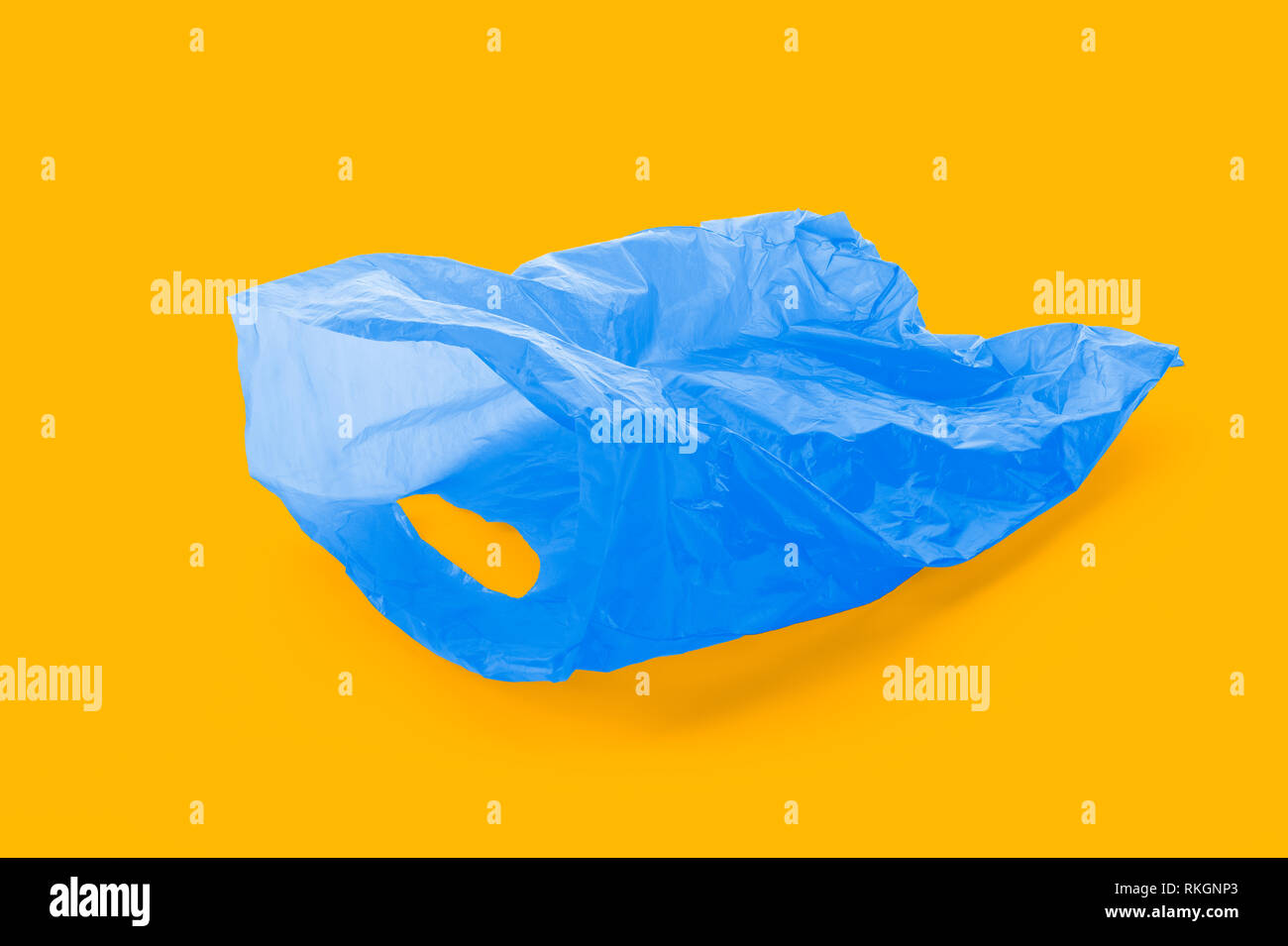 Floating vuoto azzurro sacco dei rifiuti di plastica su complementari sfondo arancione, Foto Stock