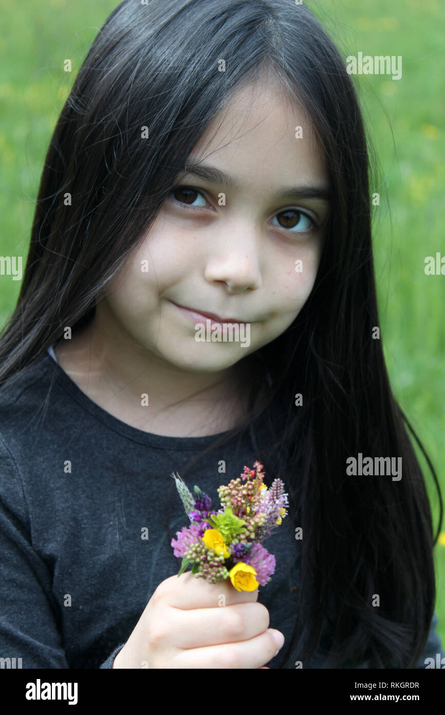 Bellissima bambina che posano per una sessione con bouquet di fiori Foto Stock