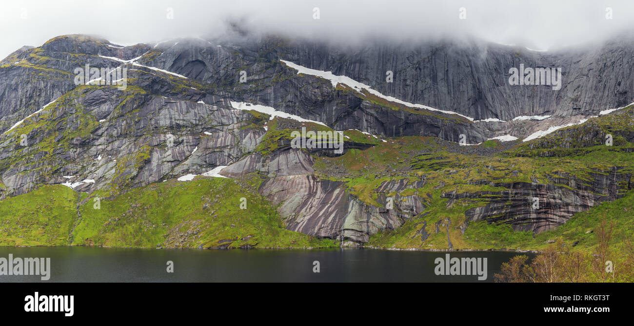 Ripide montagne risalendo dalla Storvatnet vicino Nuffjord. Sebbene sia verso la metà di giugno a livello del mare ci sono ancora macchie di neve. Foto Stock