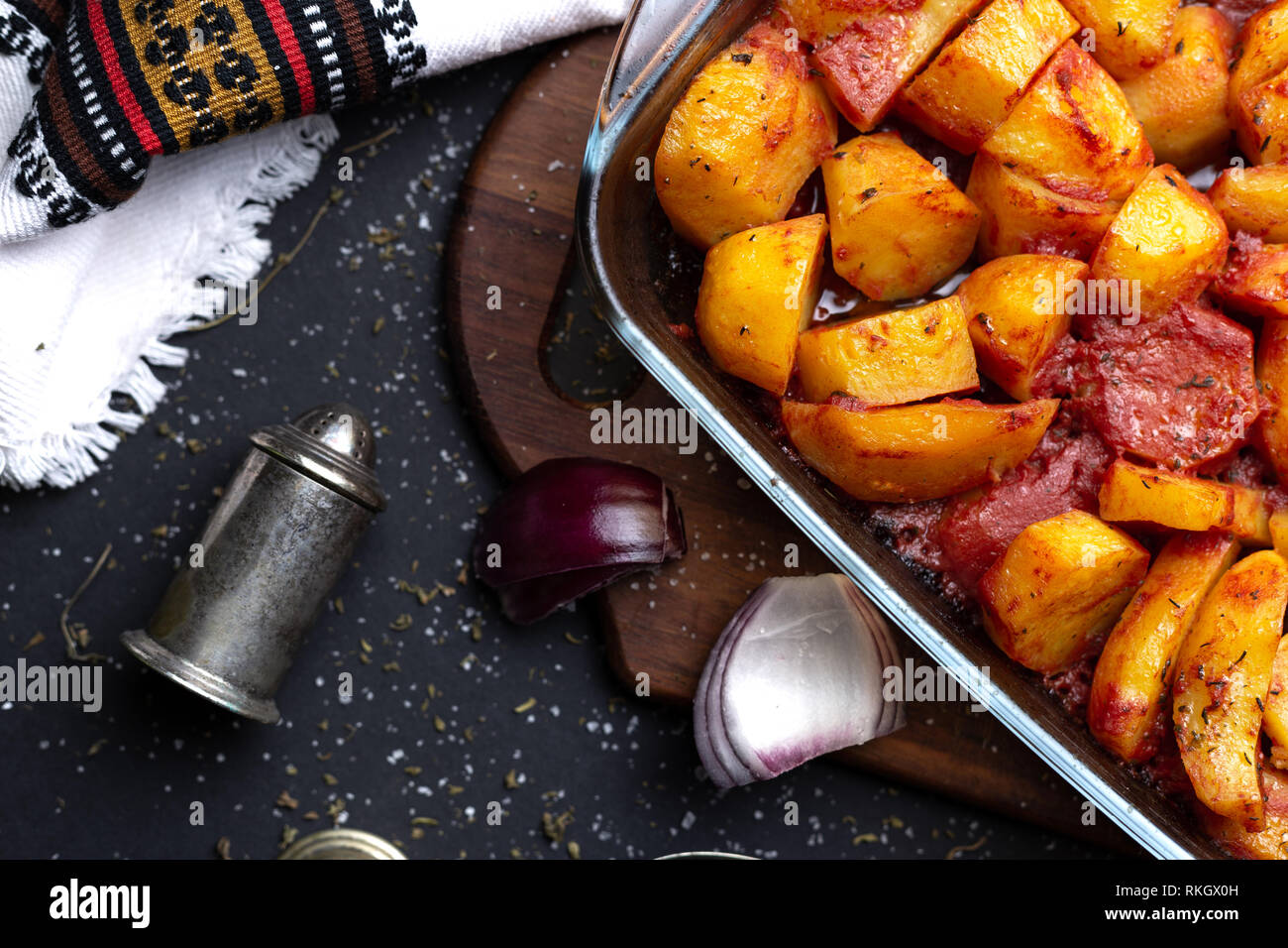 Patate al forno con spezie e succo di pomodoro. Crosta fritto, vicino il fuoco selettivo Foto Stock