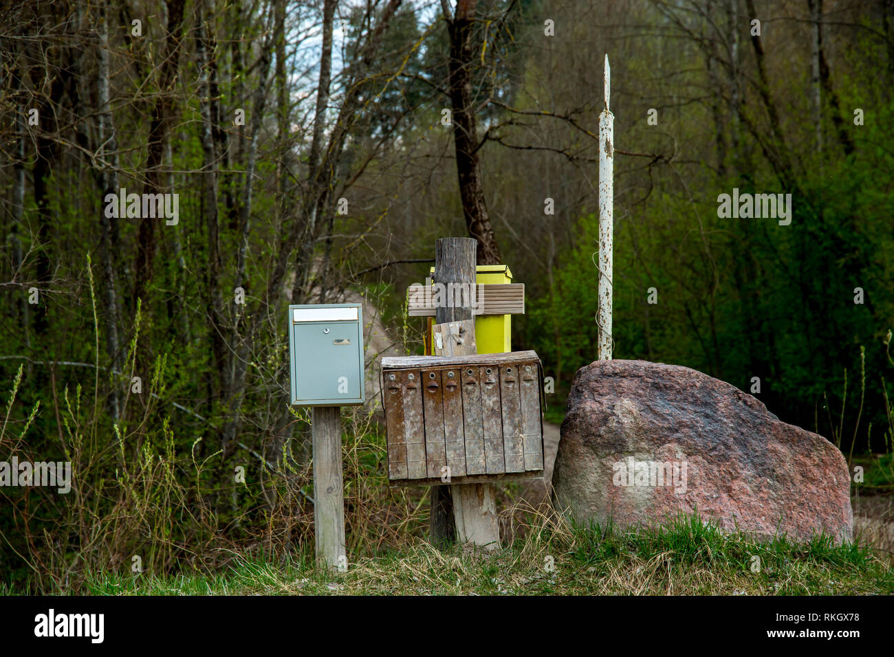 La molla del paesaggio rurale con cassetta postale. Vecchia casella postale alla strada rurale vicino a una grande pietra in Lettonia. Foto Stock