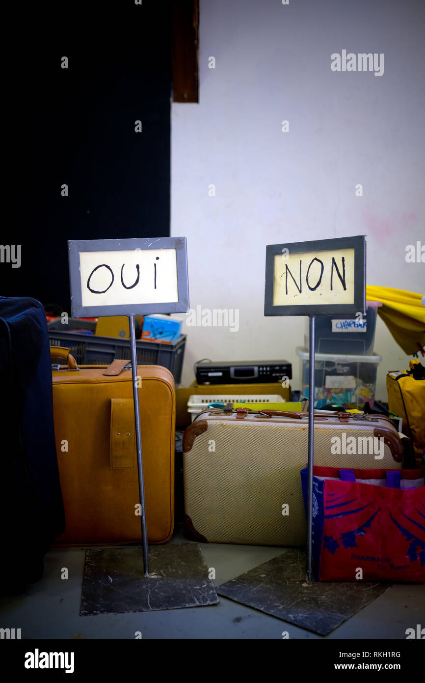 Due fatti a mano segnaletica recante le due parole francesi "oui" e "non" stand tra valigie e altri oggetti personali durante un trasloco Foto Stock