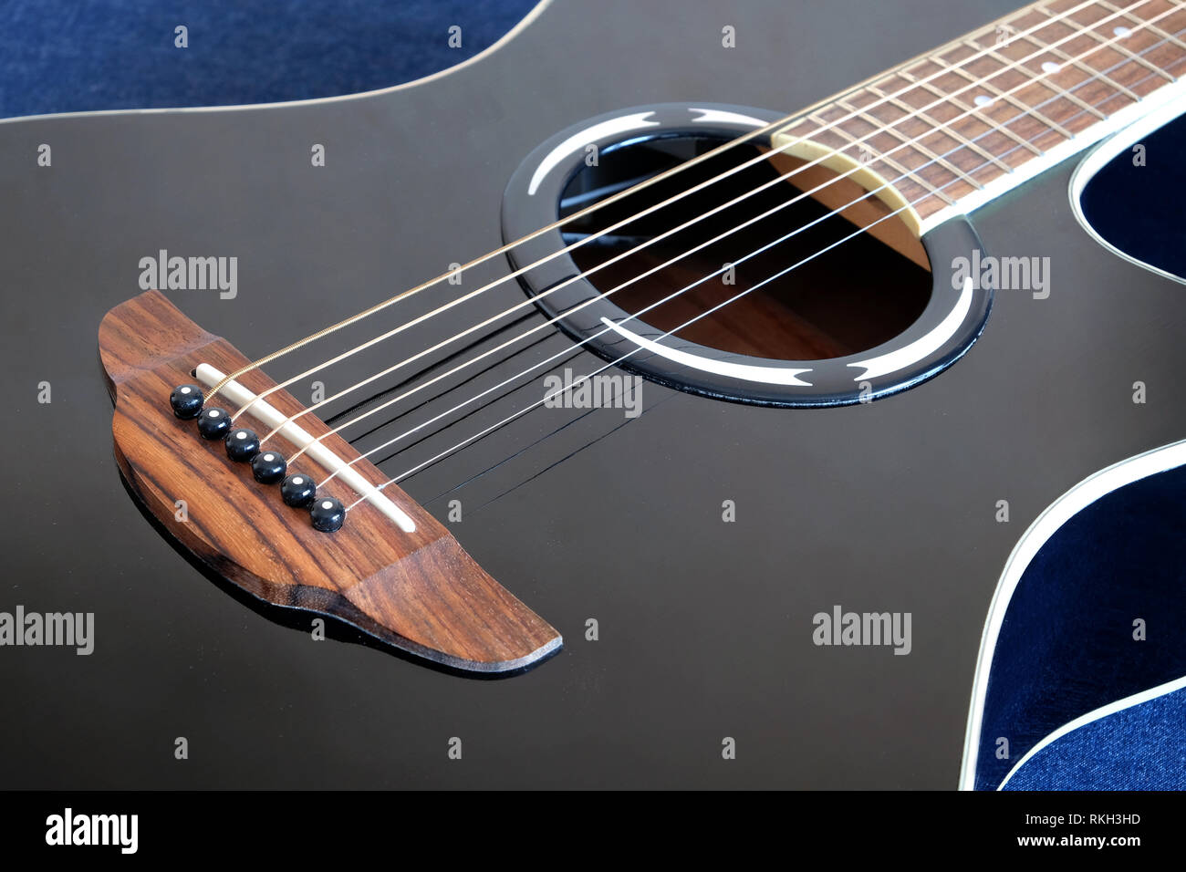Classic acoustic sei corde della chitarra di colore nero con la parte superiore in spaccato frammento su sfondo jeans vista laterale vista dettagliata Foto Stock