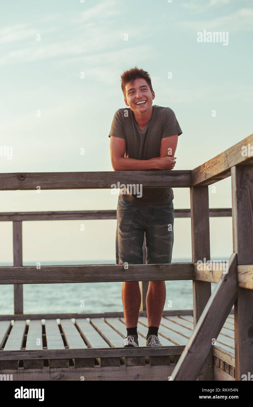 Sorridendo felice giovane uomo in piedi su un molo sul mare durante il periodo estivo vavations. Copia per lo spazio per il testo Foto Stock