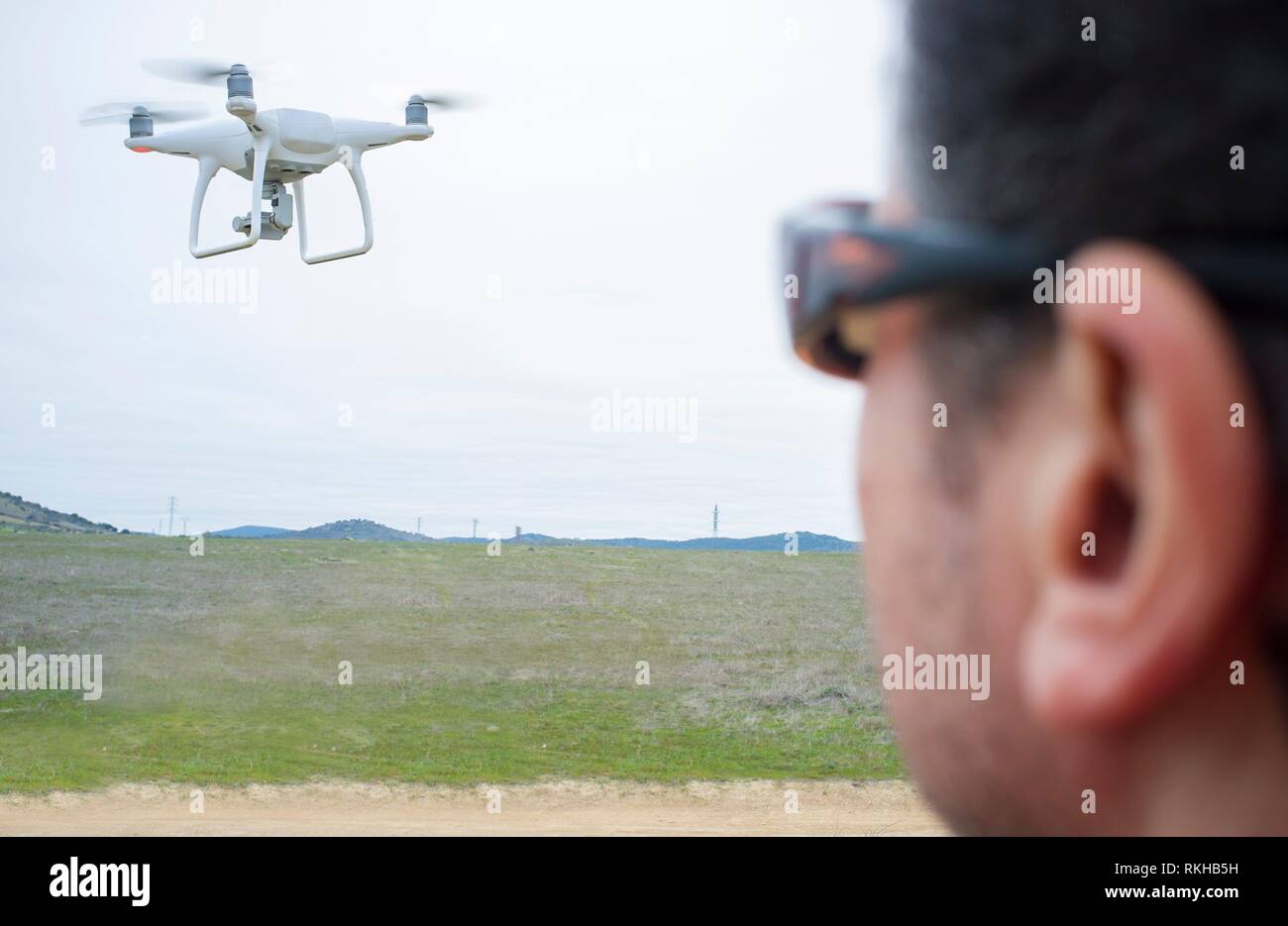Pilot flying drone un giorno nuvoloso sulla campagna. Aproaching manovra. Foto Stock