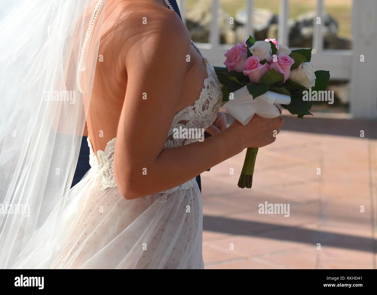 Giovane sposa in pizzo bianco halter top abito da sposa a piedi giù per la corsia a un hotel in un resort tropicale. Matrimonio in un giardino tropicale. Foto Stock