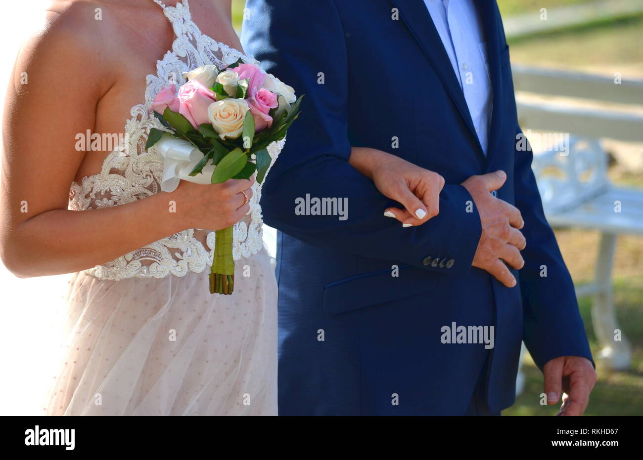 Giovane sposa in pizzo bianco halter top abito da sposa a piedi giù per la corsia a un hotel in un resort tropicale. Matrimonio in un giardino tropicale. Foto Stock