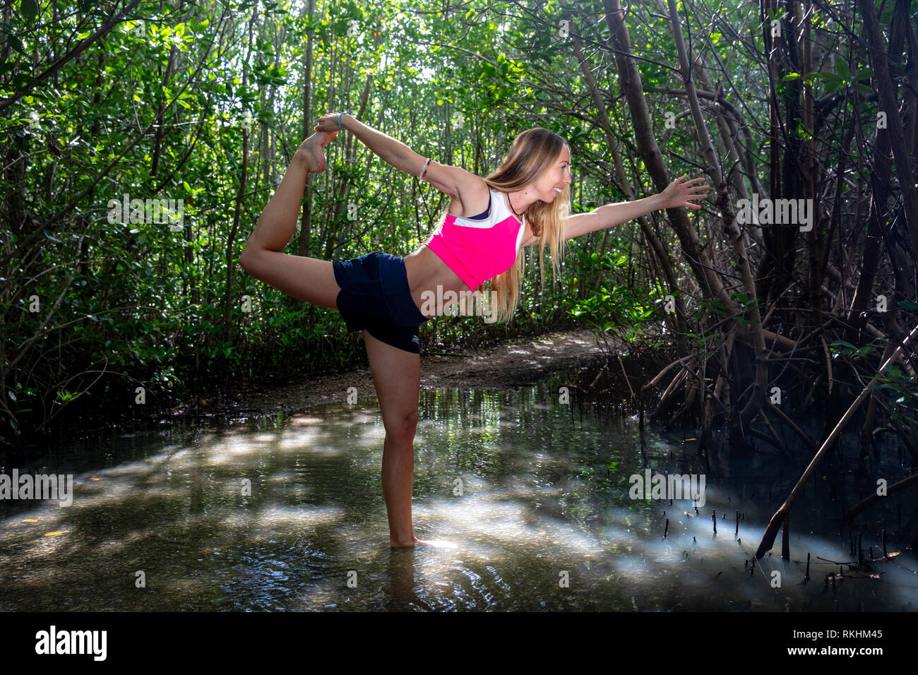 Giovane donna a praticare yoga (Signore della danza pongono - Natarajasana) in un ambiente naturale - Fort Lauderdale, Florida, Stati Uniti d'America Foto Stock