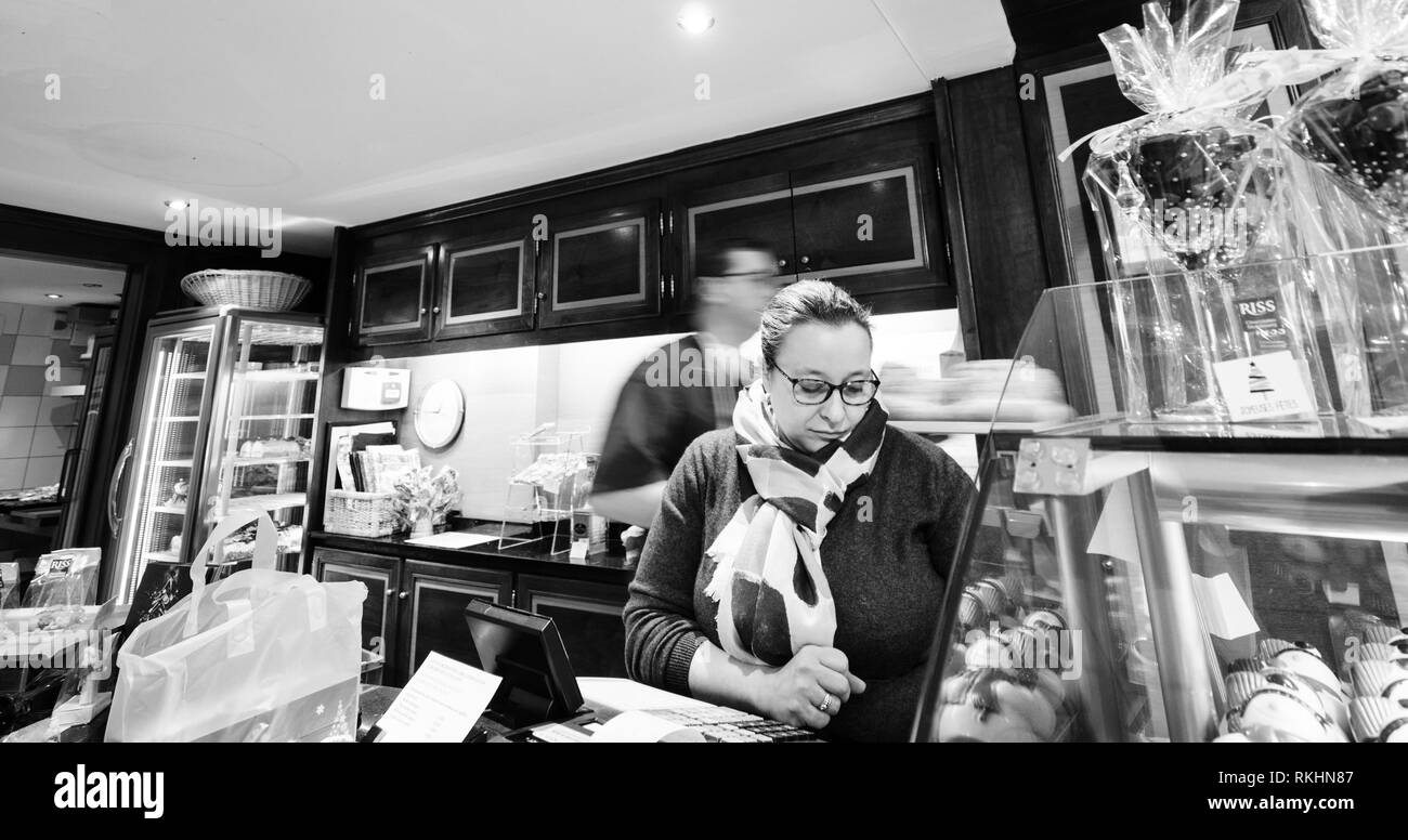 Strasburgo, Francia - 29 DIC 2018: Cassiere che servono clienti in francese tradizionale negozio di pasticceria, Riss vendono dolci durante le vacanze invernali con selezioni multiple di pasticceria alsaziana in bianco e nero Foto Stock