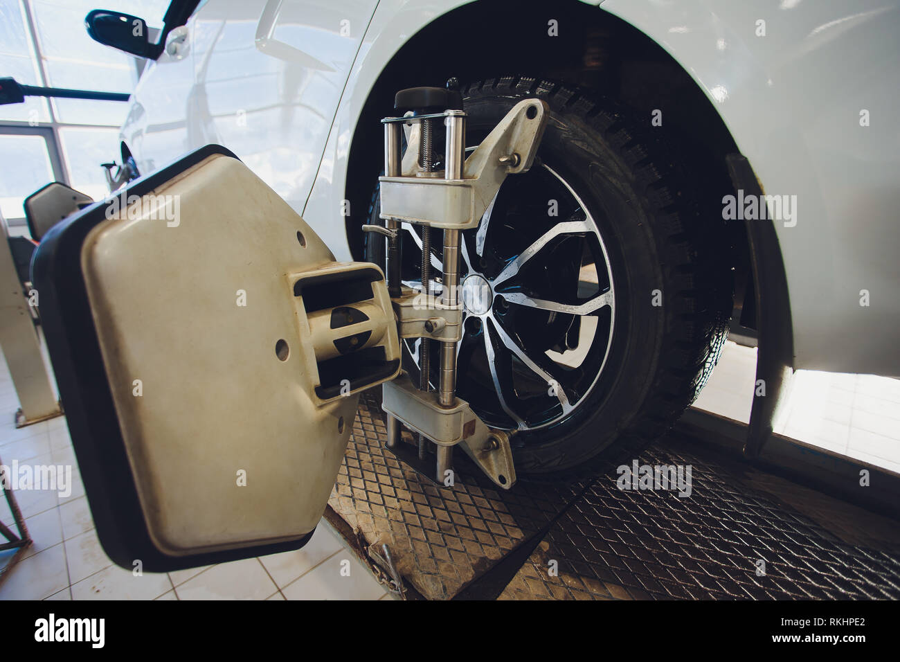 Una vettura sul volante della macchina equilibratrice e calibrare con riflettore laser fissare su ciascun pneumatico al centro la guida regolare in garage Foto Stock