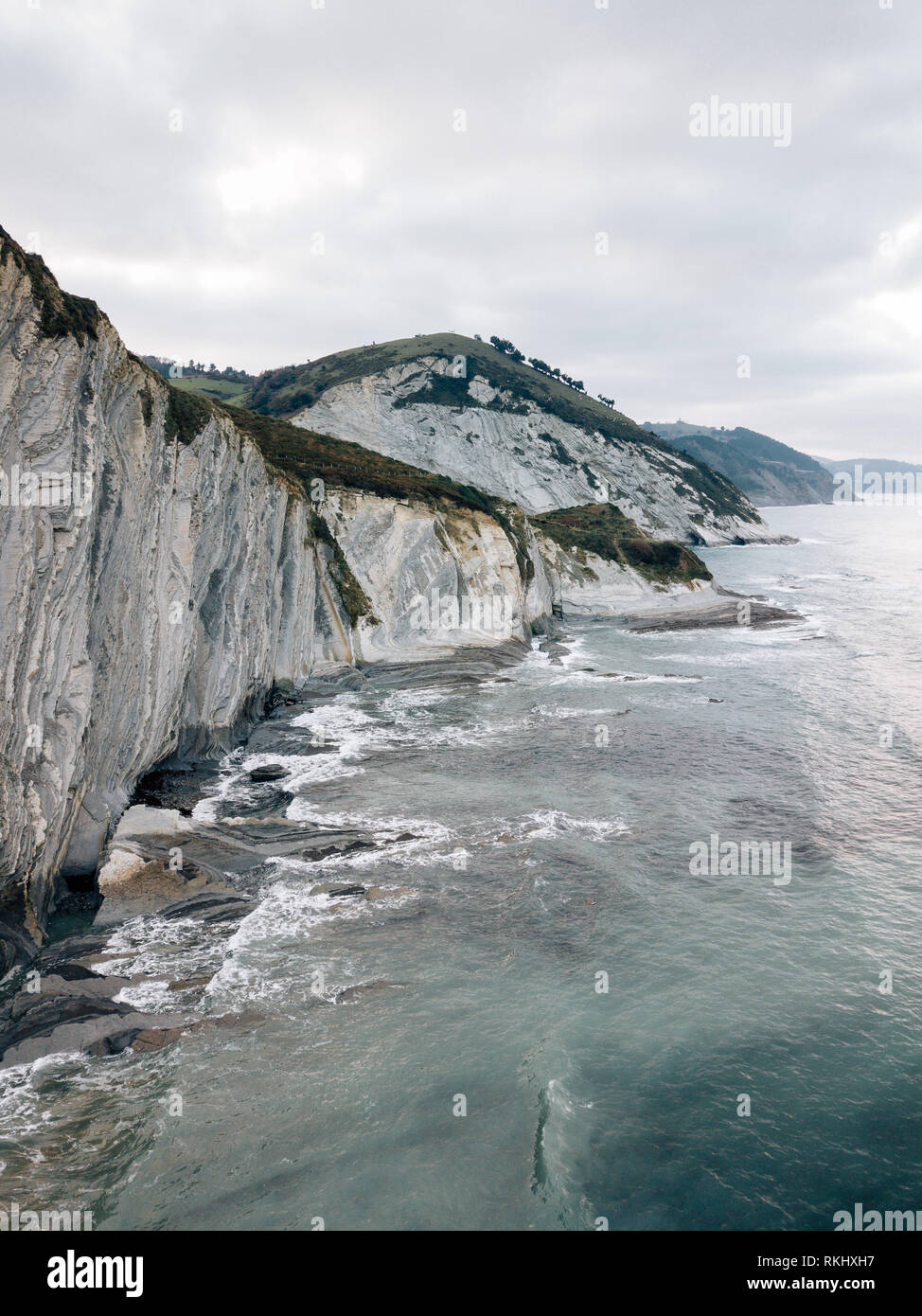 Ondulazione del mare nei pressi di colline verdi Foto Stock