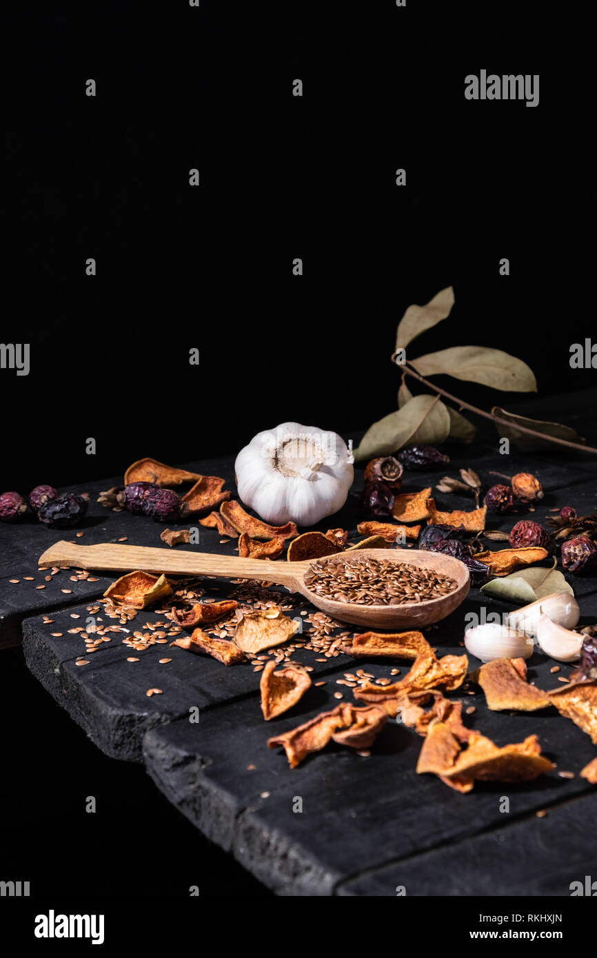 Aglio, frutta secca e semi di rustico scuro dello sfondo. Foto artistiche di aglio e frutta secca su una vecchia tavola nera girato in chiave di basso stile ciaroscurro Foto Stock