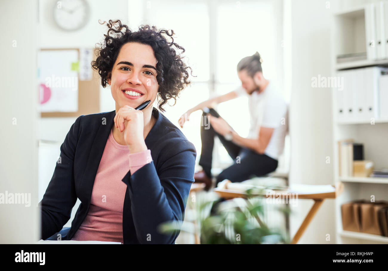Un Ritratto di giovane imprenditrice seduto in un ufficio moderno. Foto Stock