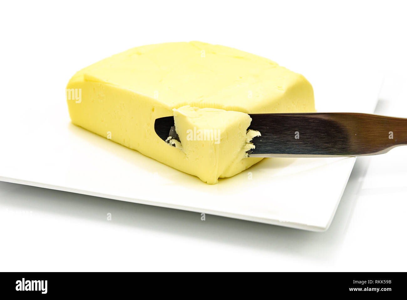 Pezzo di burro con argento coltello sulla piastra isolata su uno sfondo bianco in close-up Foto Stock