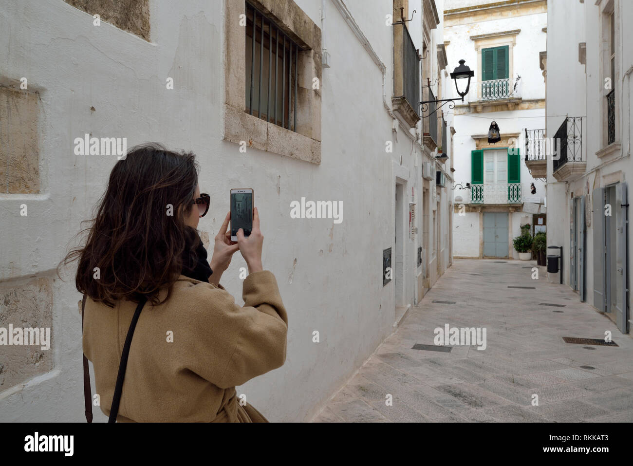 Donna di scattare le foto in piccola strada a Locorotondo centro storico, Italia Foto Stock