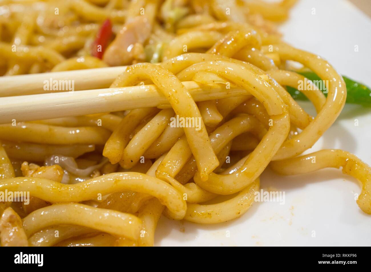 Udon tra bacchette. Tipo di noodle spesso utilizzati in cucina giapponese. Foto Stock