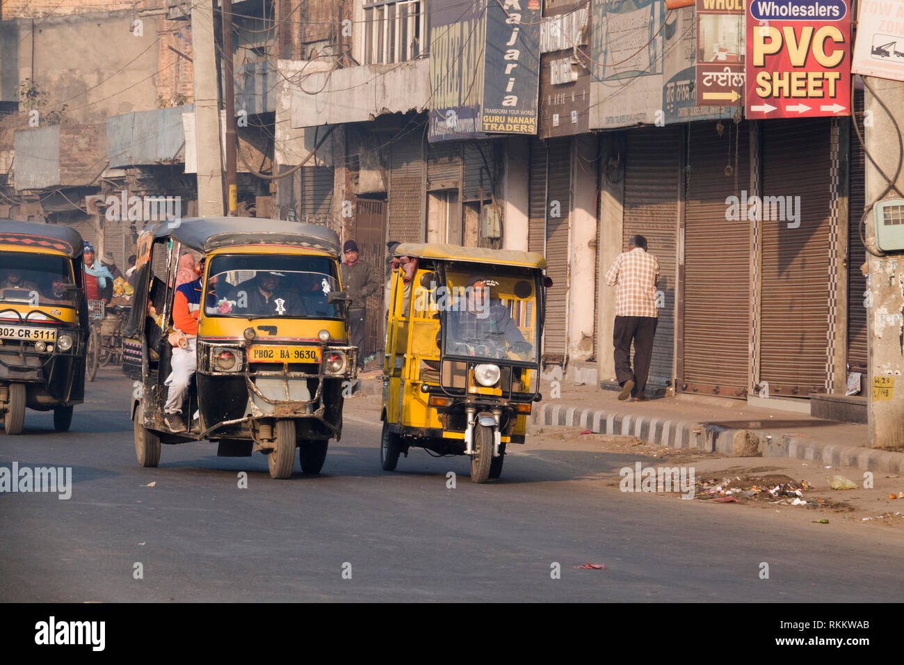 La benzina e elettrico più piccolo auto rickshaw fianco a fianco in movimento di Amritsar Punjab, India Foto Stock