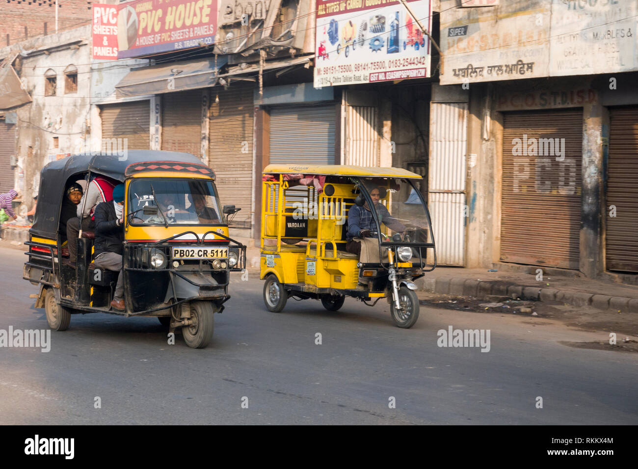 La benzina e elettrico più piccolo auto rickshaw fianco a fianco in movimento di Amritsar Punjab, India Foto Stock