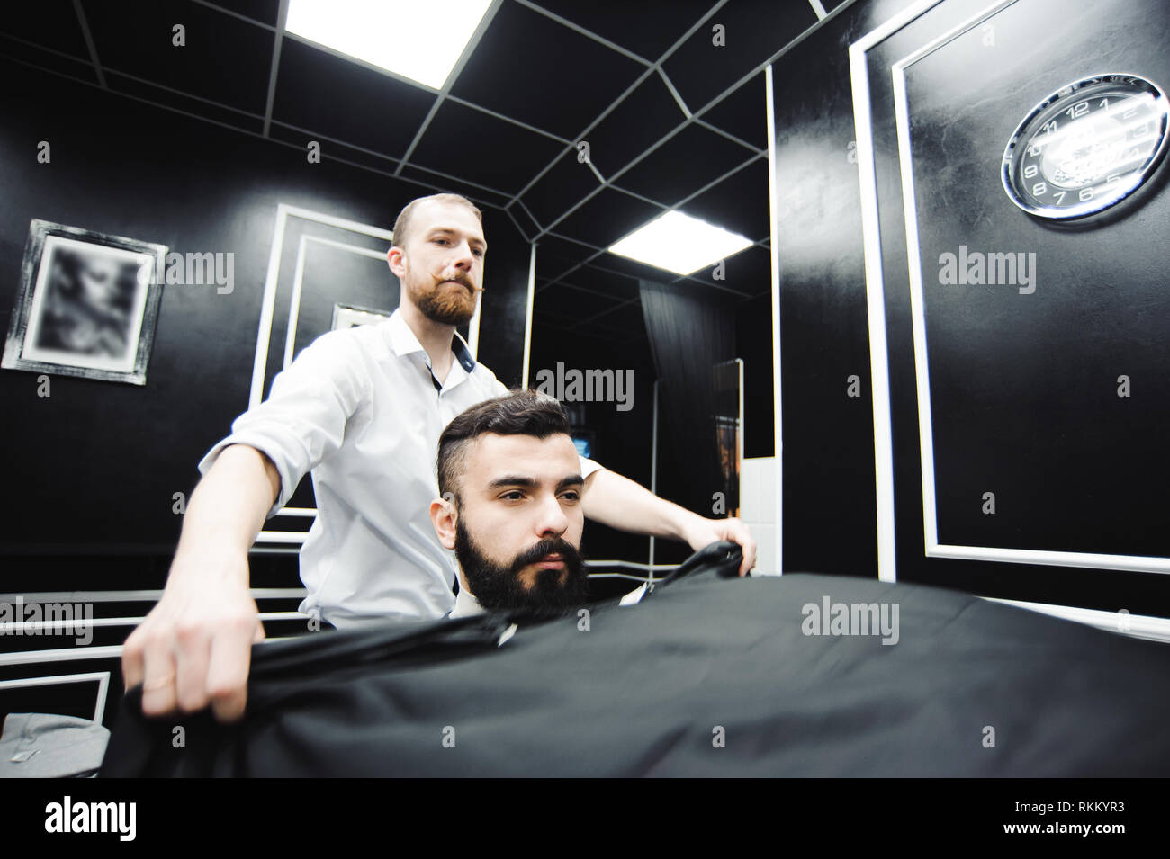 Master taglia i capelli e la barba di uomini nel barbiere e parrucchiere Foto Stock