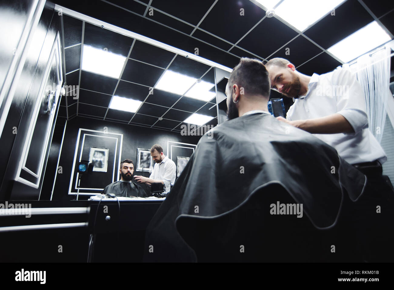 Master taglia i capelli e la barba di uomini nel barbiere e parrucchiere Foto Stock